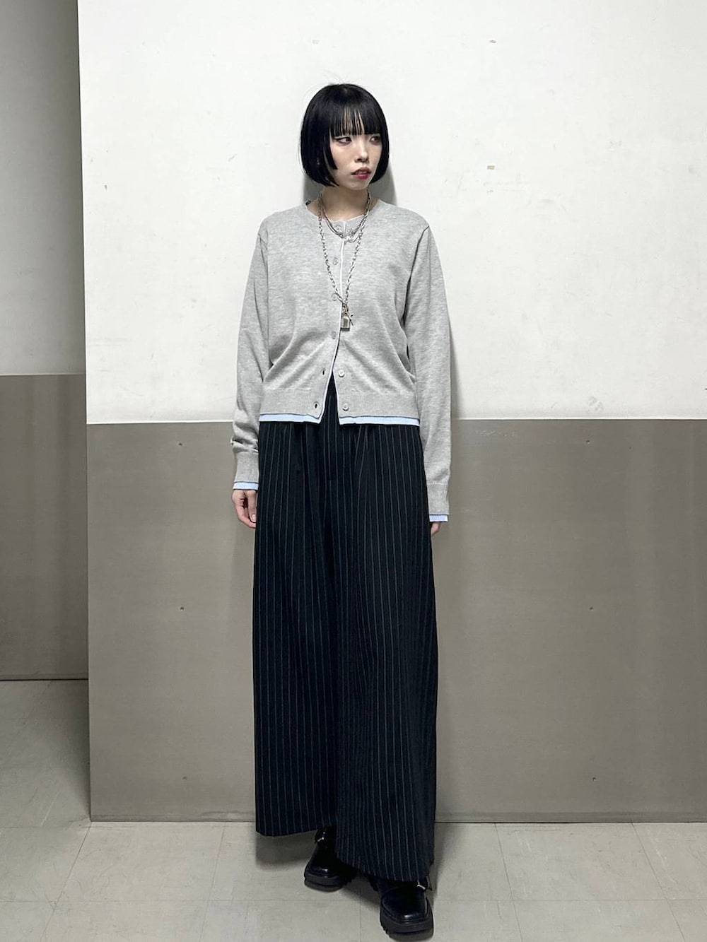 ブラック系のブーツ、ブラック系のスラックス、グレー系のカーディガン/ボレロを着用したレディースの冬コーディネートの2枚目の写真