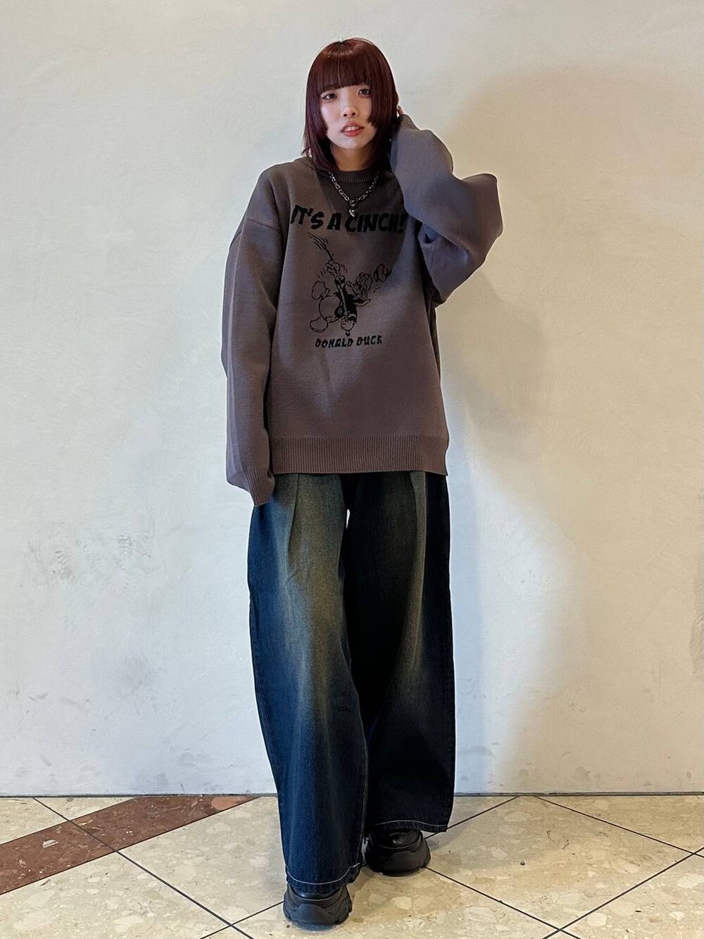 ブラック系のスニーカー、ブルー系のデニムパンツ、グレー系のニット/セーターを着用したレディースの冬コーディネートの2枚目の写真