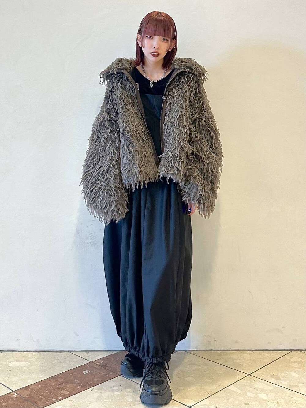 ブラック系のスニーカー、ブラック系のTシャツ/カットソー、ブラウン系のブルゾンを着用したレディースの秋コーディネートの2枚目の写真