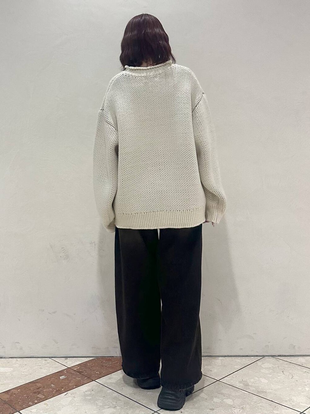 ブラック系のスニーカー、ホワイト系のニット/セーター、ブラック系のデニムパンツを着用したレディースの冬コーディネートの4枚目の写真