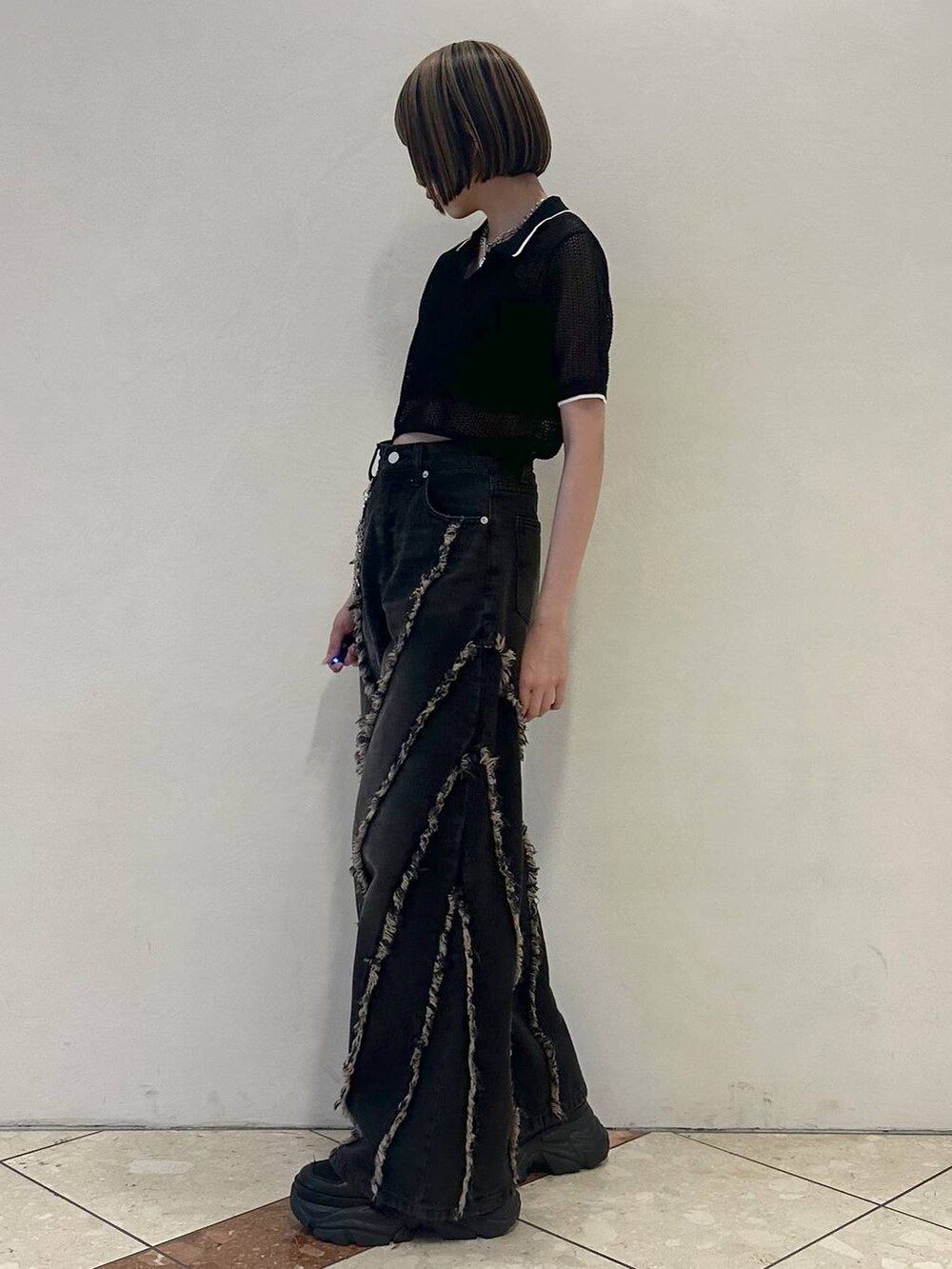 ブラック系のスニーカー、ブラック系のニット/セーター、ブラック系のデニムパンツを着用したレディースの夏コーディネートの3枚目の写真