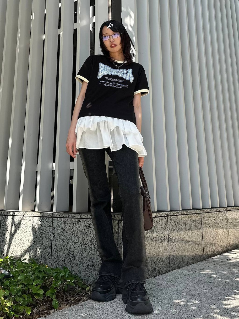 ブラック系のスニーカー、ブラック系のデニムパンツ、ブラウン系のショルダーバッグを着用したレディースの夏コーディネートの2枚目の写真