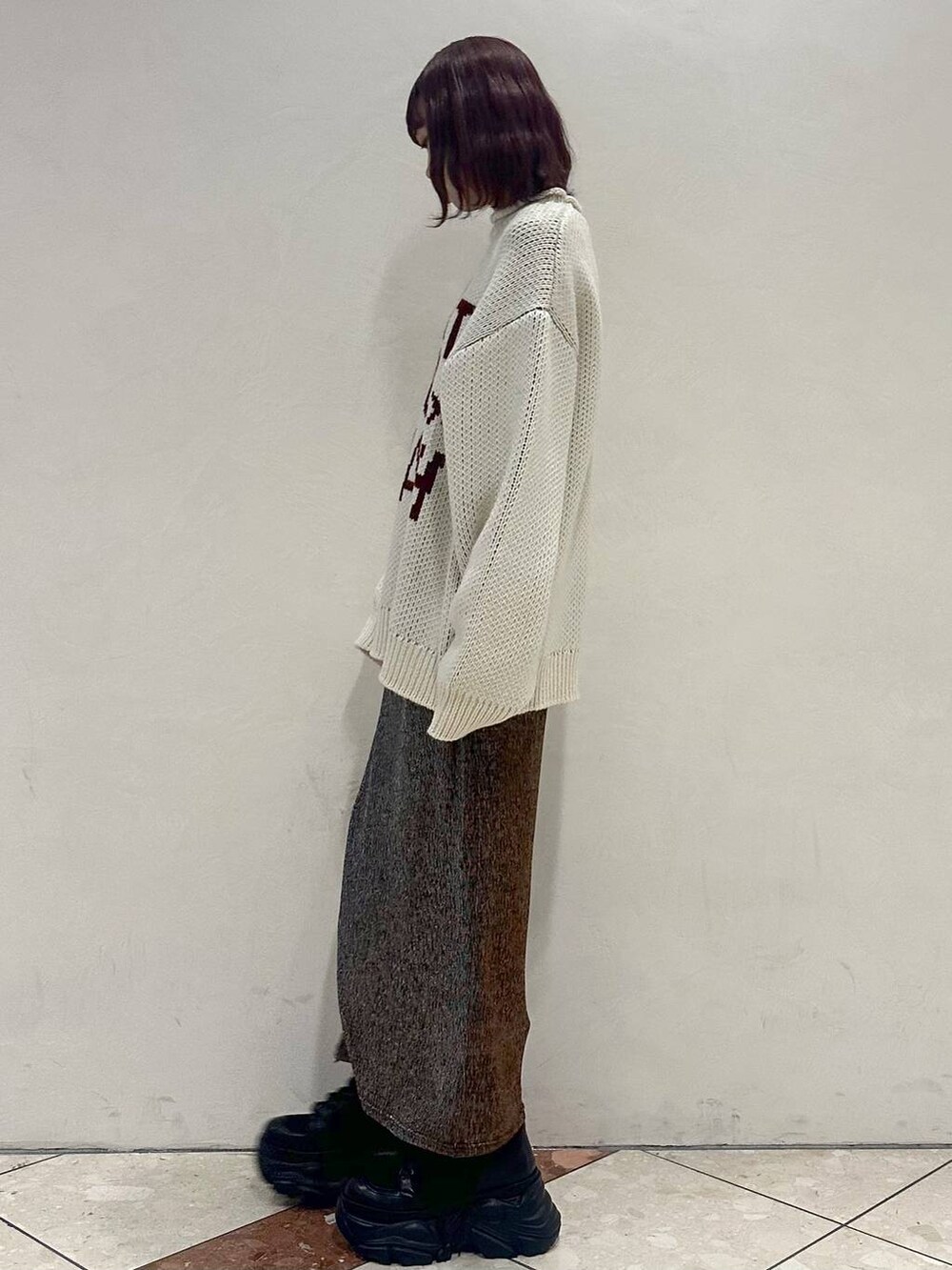 ブラック系のブーツ、ホワイト系のニット/セーター、ゴールド系のスカートを着用したレディースの冬コーディネートの3枚目の写真