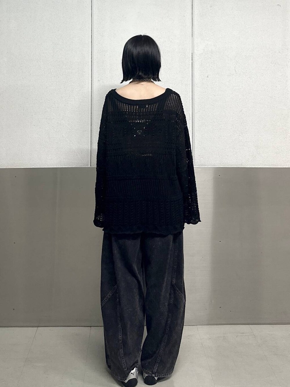 ブラック系のデニムパンツ、ブラック系のニット/セーター、ブラック系のネックレスを着用したレディースの春コーディネートの4枚目の写真