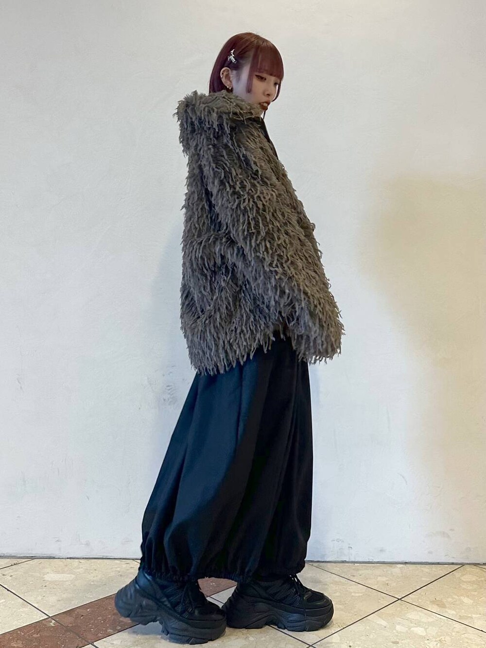 ブラック系のスニーカー、ブラック系のTシャツ/カットソー、ブラウン系のブルゾンを着用したレディースの秋コーディネートの3枚目の写真