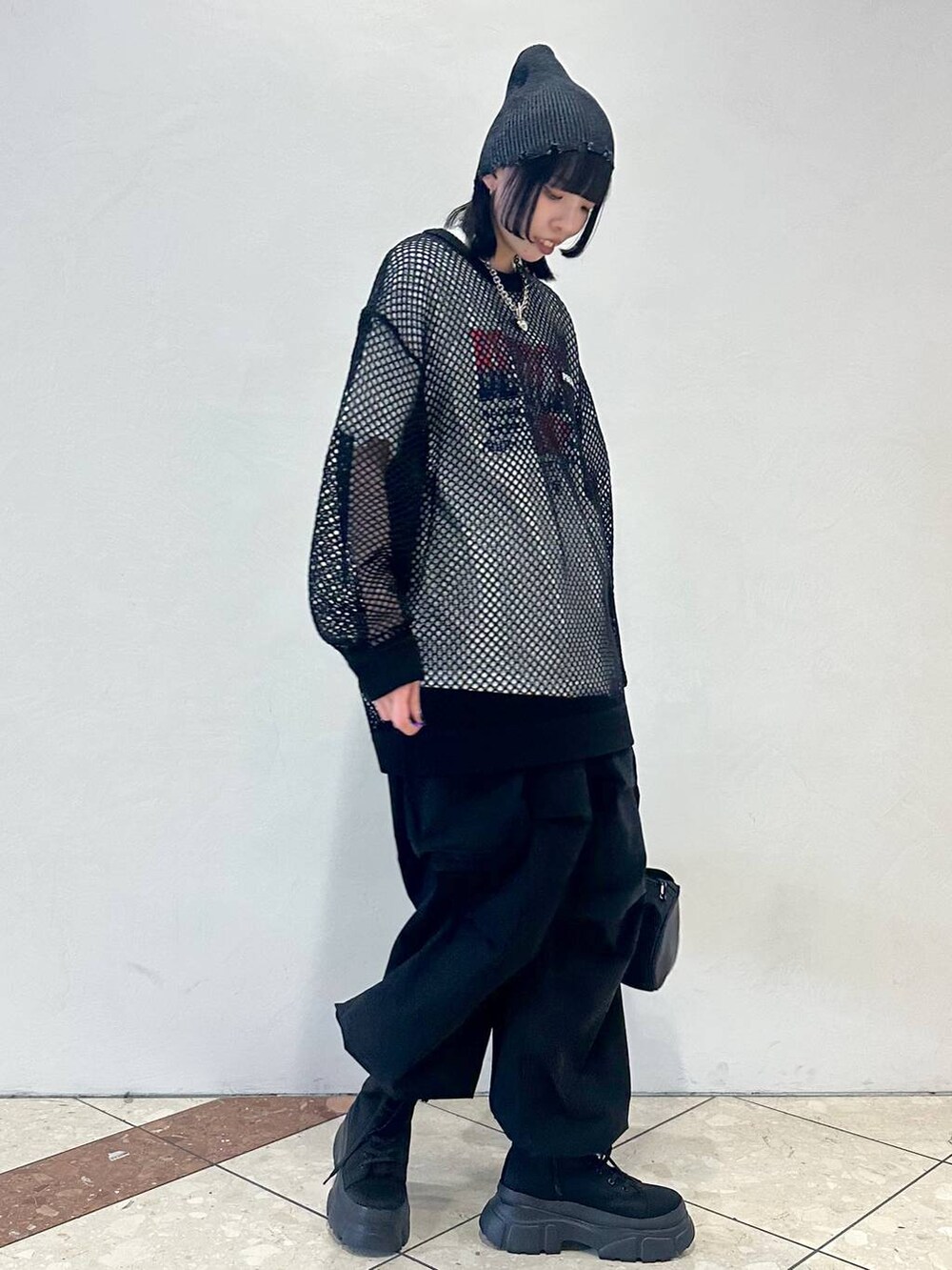 ブラック系のドラムバッグ、ホワイト系のTシャツ/カットソー、ブラック系のブーツを着用したレディースの春コーディネートの2枚目の写真