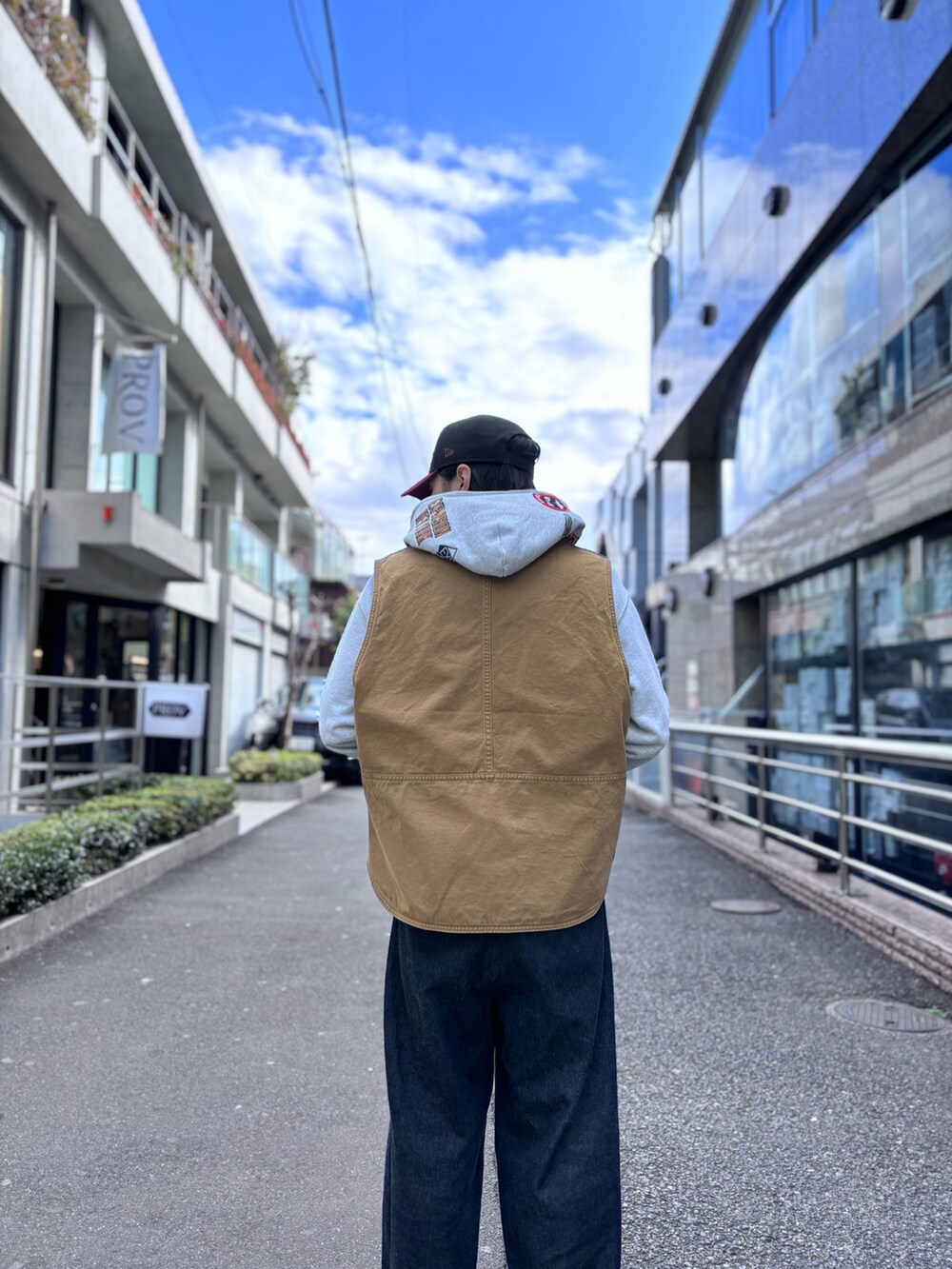 グレー系のパーカー、ベージュ系のベスト、レッド系のキャップを着用したメンズの冬コーディネートの2枚目の写真