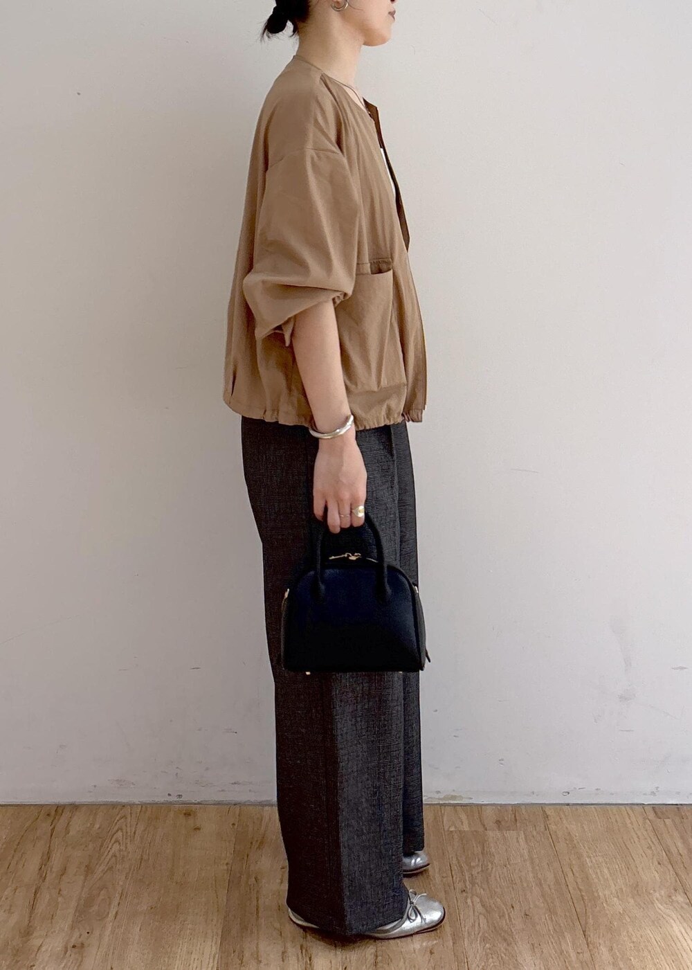 ベージュ系のブルゾン、グレー系のスラックス、ブラック系のショルダーバッグを着用したレディースの秋コーディネートの3枚目の写真