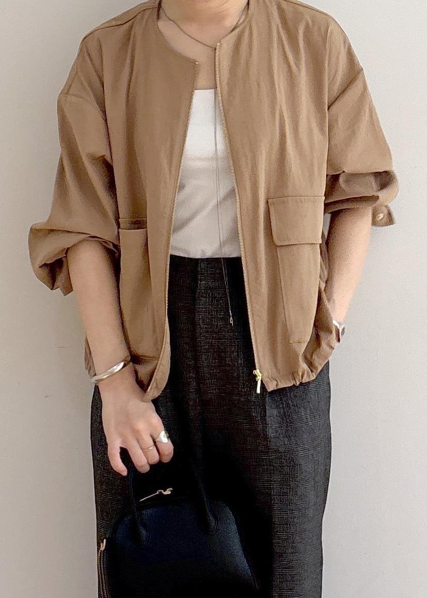 ベージュ系のブルゾン、グレー系のスラックス、ブラック系のショルダーバッグを着用したレディースの秋コーディネートの2枚目の写真