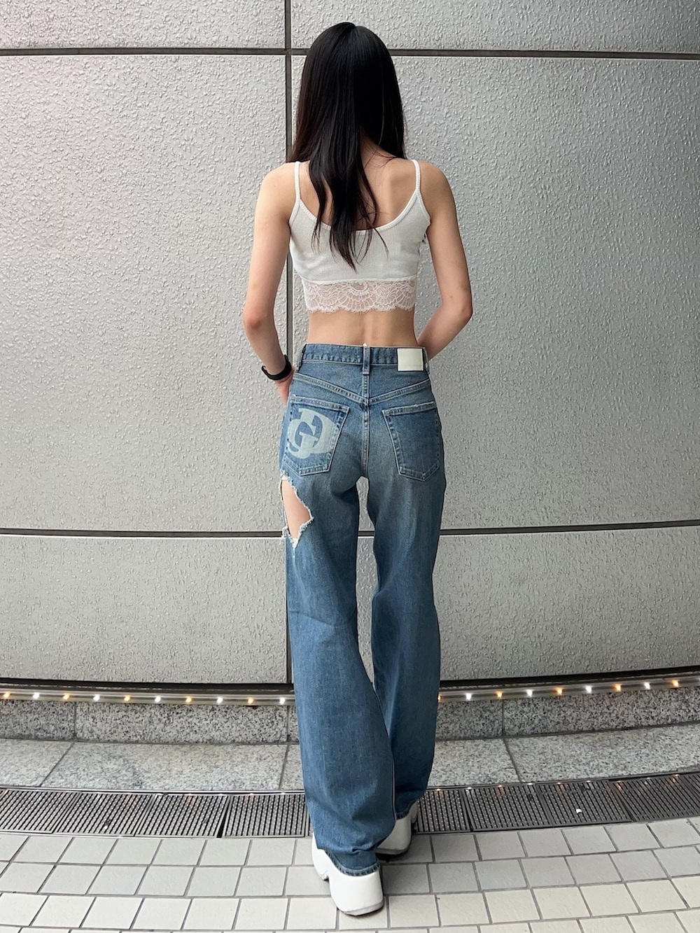 ホワイト系のキャミソール、ブルー系のデニムパンツ、ホワイト系のサンダルを着用したレディースの夏コーディネートの3枚目の写真