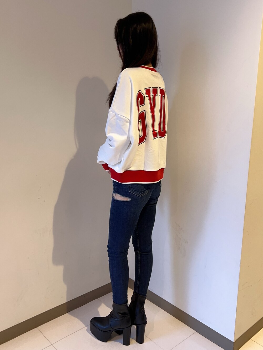 ホワイト系のスウェット、ブルー系のデニムパンツ、ブラック系のブーツを着用したレディースの夏コーディネートの2枚目の写真