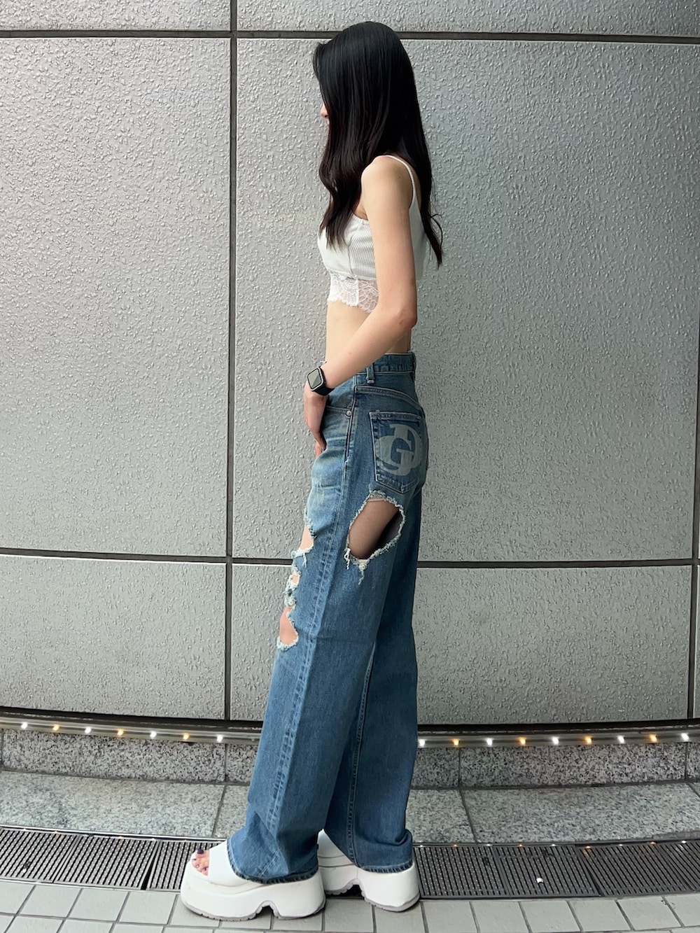 ホワイト系のキャミソール、ブルー系のデニムパンツ、ホワイト系のサンダルを着用したレディースの夏コーディネートの2枚目の写真