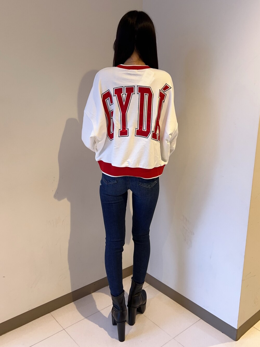 ホワイト系のスウェット、ブルー系のデニムパンツ、ブラック系のブーツを着用したレディースの夏コーディネートの3枚目の写真