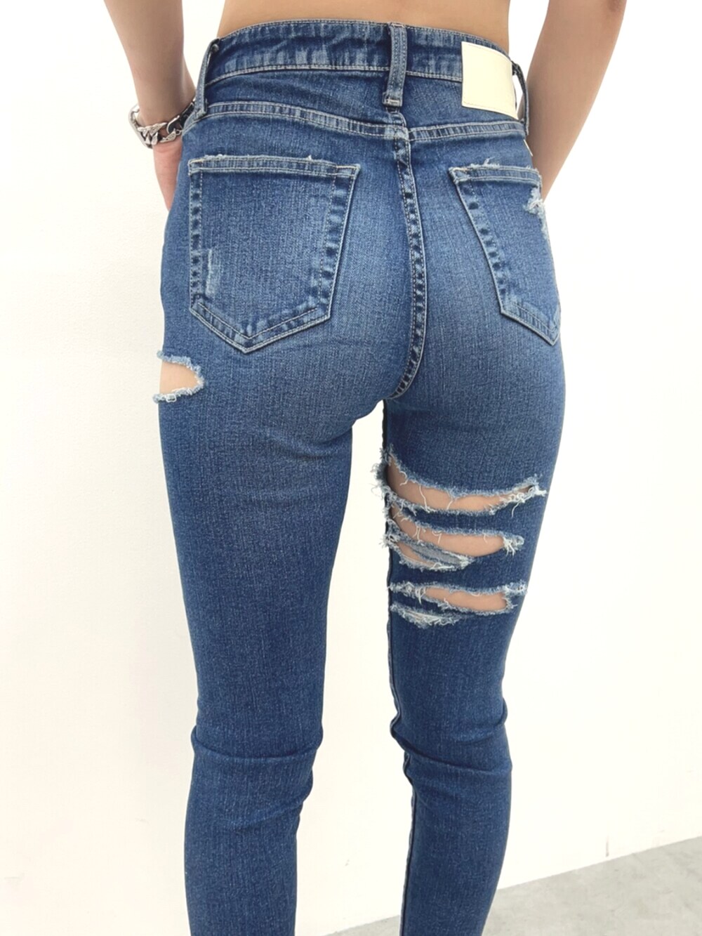 ホワイト系のサンダル、ホワイト系のキャミソール、ブルー系のデニムパンツを着用したレディースの夏コーディネートの6枚目の写真