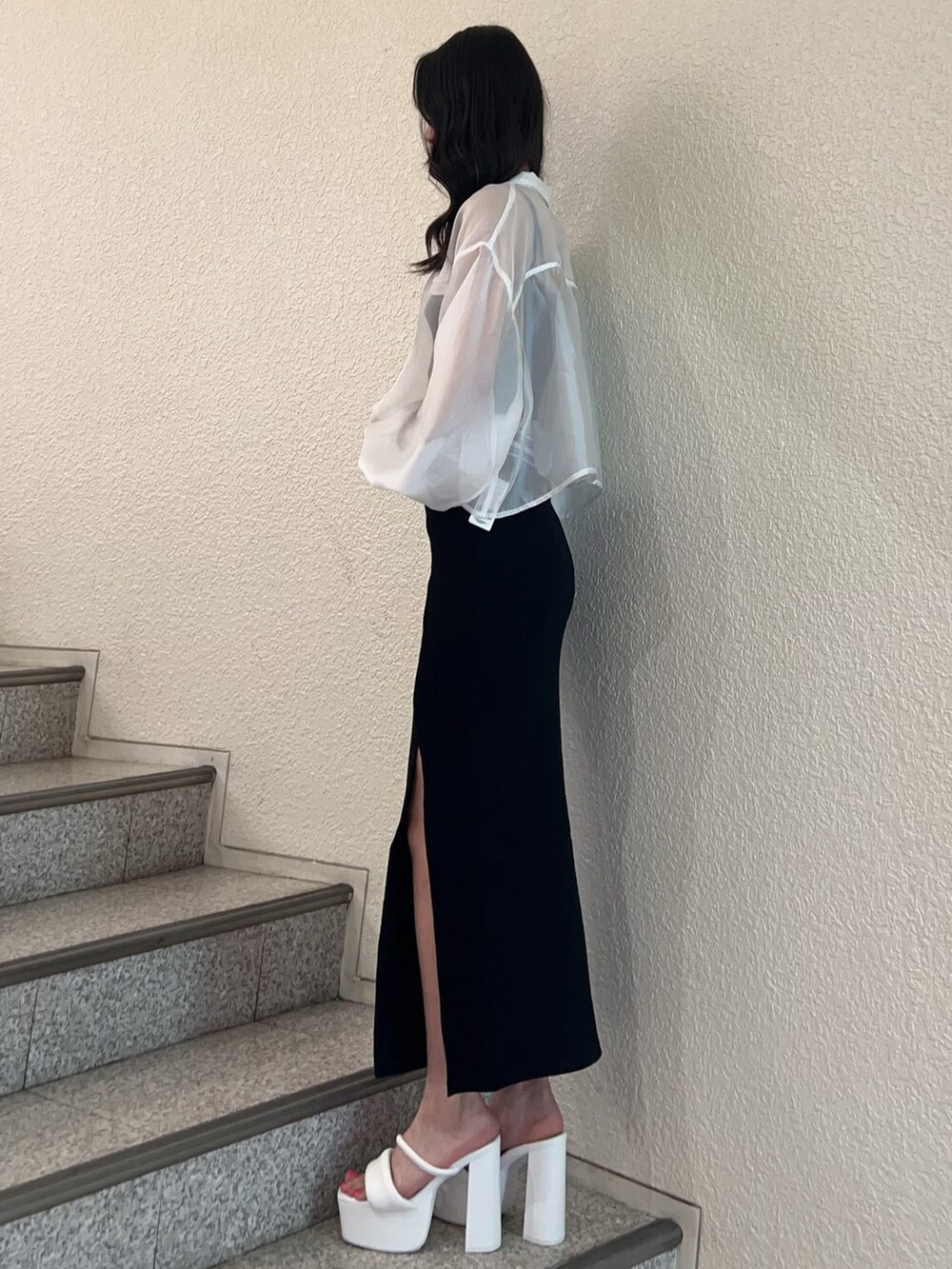 ホワイト系のシャツ/ブラウス、ブラック系のスカート、ホワイト系のサンダルを着用したレディースの春コーディネートの2枚目の写真