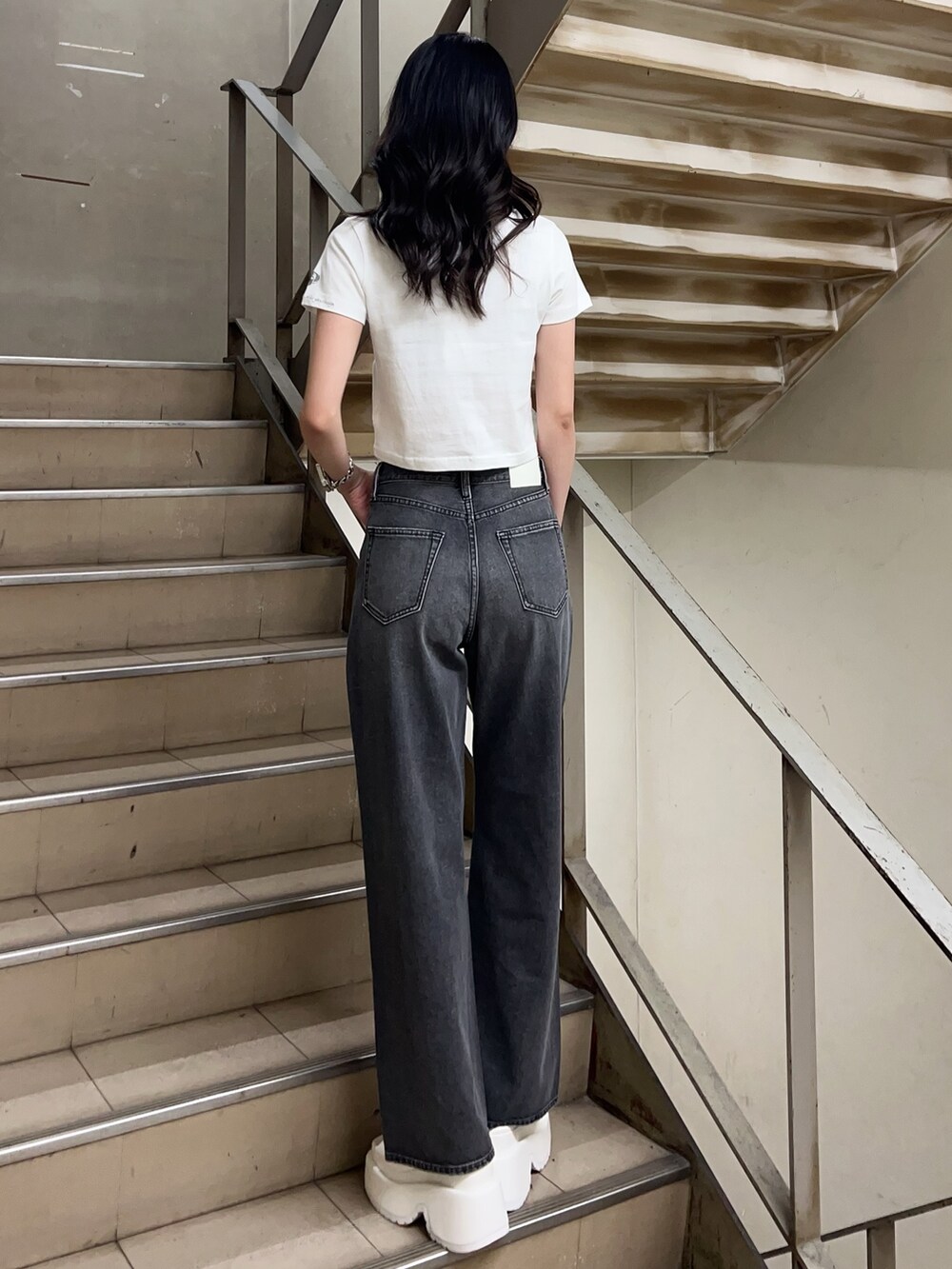 ホワイト系のTシャツ/カットソー、ブラック系のデニムパンツ、ホワイト系のサンダルを着用したレディースの春コーディネートの3枚目の写真