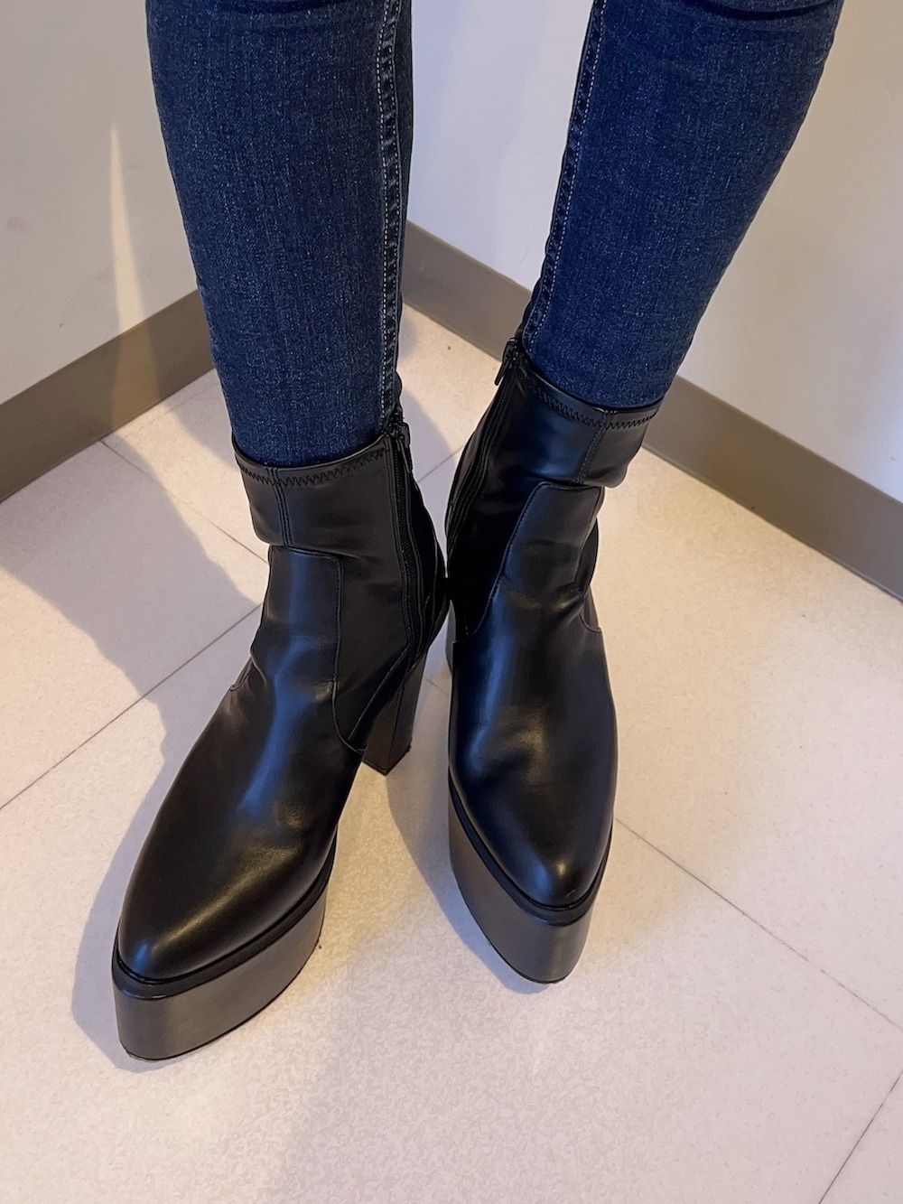 ホワイト系のスウェット、ブルー系のデニムパンツ、ブラック系のブーツを着用したレディースの夏コーディネートの7枚目の写真