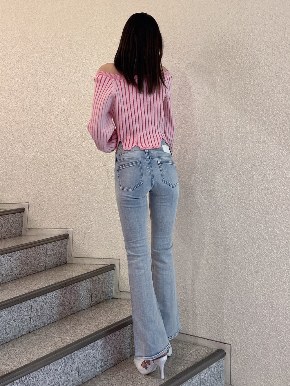 ブルー系のデニムパンツ、ピンク系のニット/セーター、ホワイト系のパンプスを着用したレディースの冬コーディネートの3枚目の写真