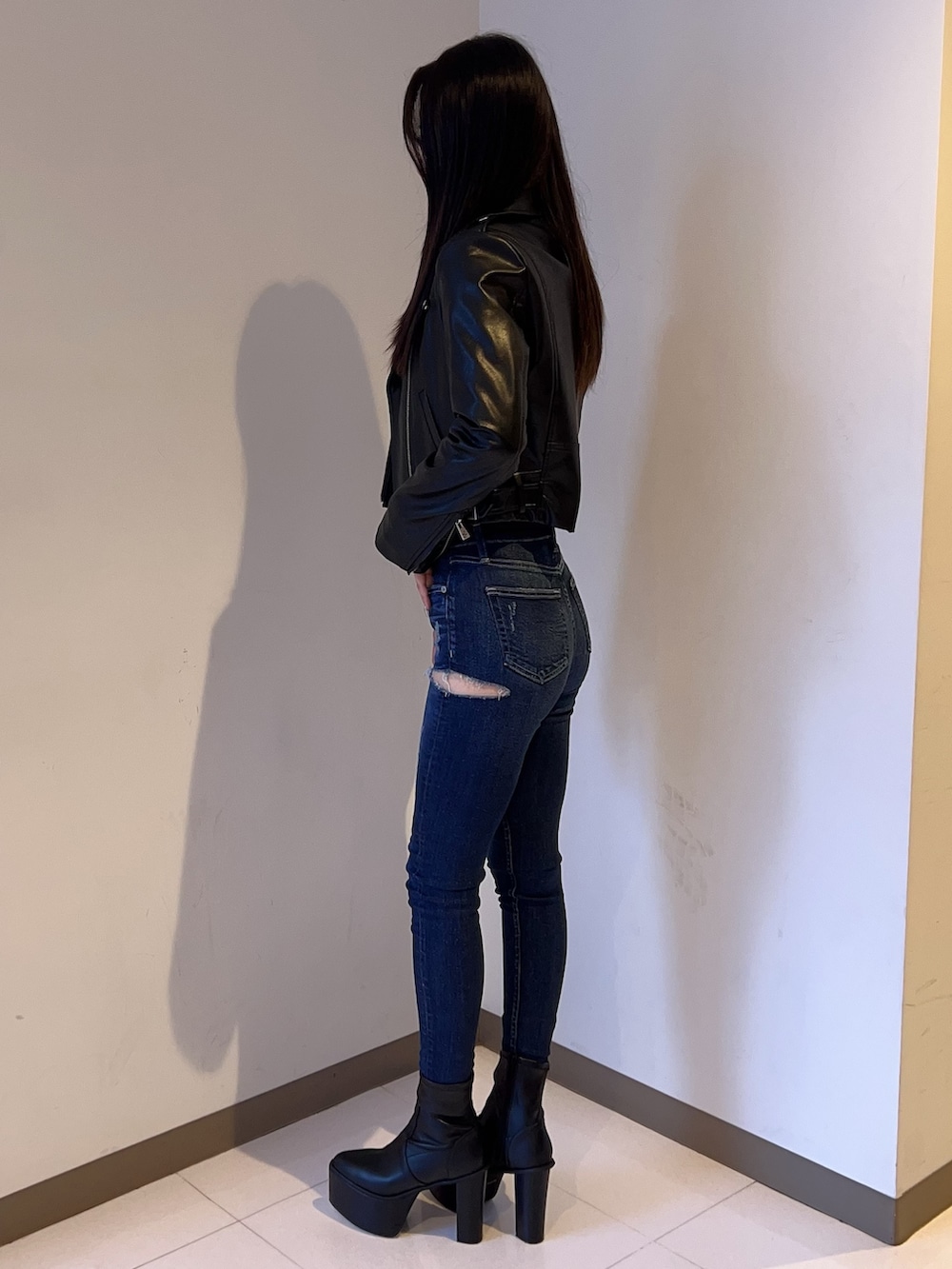 ブラック系のライダースジャケット、ブラック系のニット/セーター、ブルー系のデニムパンツを着用したレディースの夏コーディネートの2枚目の写真