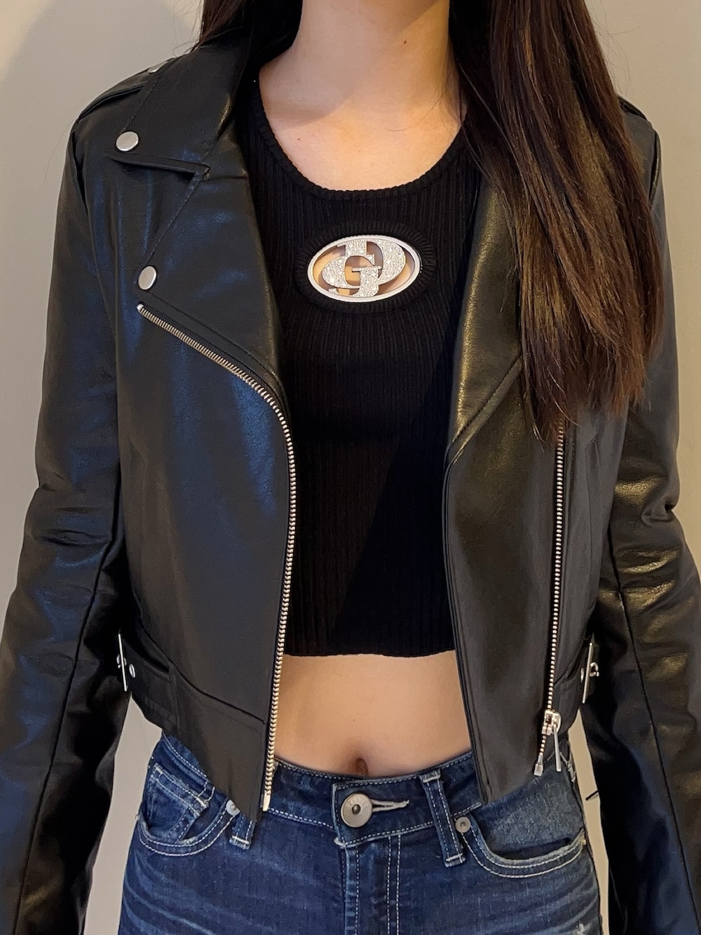 ブラック系のライダースジャケット、ブラック系のニット/セーター、ブルー系のデニムパンツを着用したレディースの夏コーディネートの4枚目の写真