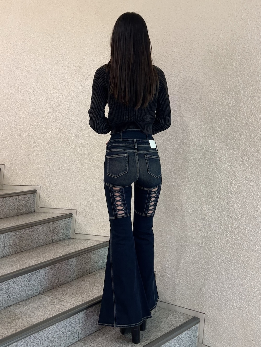 ブルー系のデニムパンツ、ブラック系のニット/セーター、ブラック系のブーツを着用したレディースの秋コーディネートの3枚目の写真