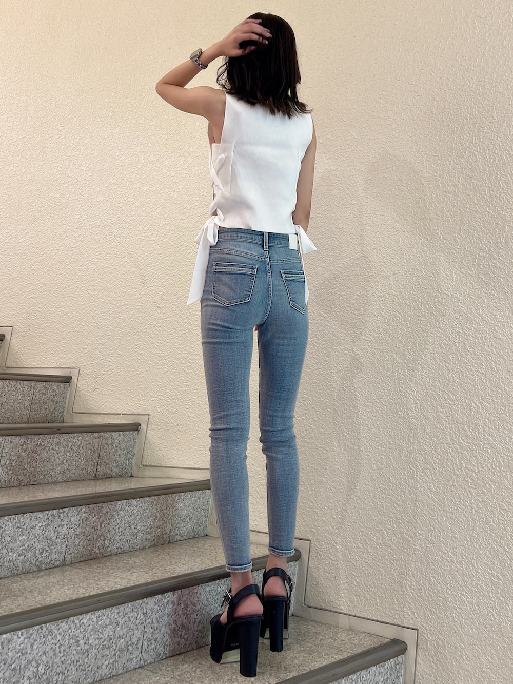 ホワイト系のニット/セーター、ブルー系のデニムパンツ、ブラック系のサンダルを着用したレディースの夏コーディネートの3枚目の写真