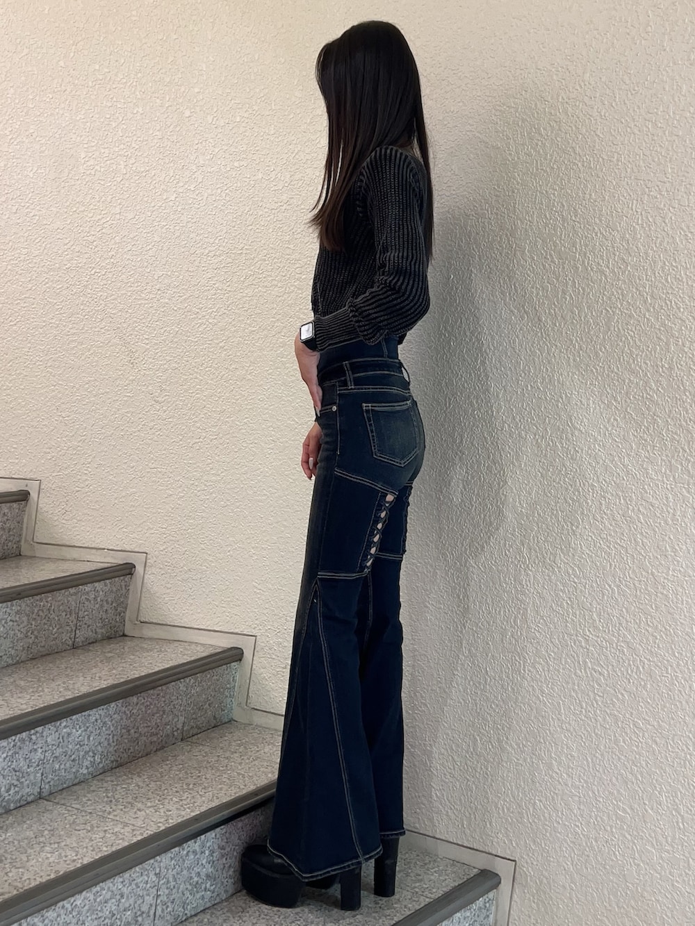 ブルー系のデニムパンツ、ブラック系のニット/セーター、ブラック系のブーツを着用したレディースの秋コーディネートの2枚目の写真