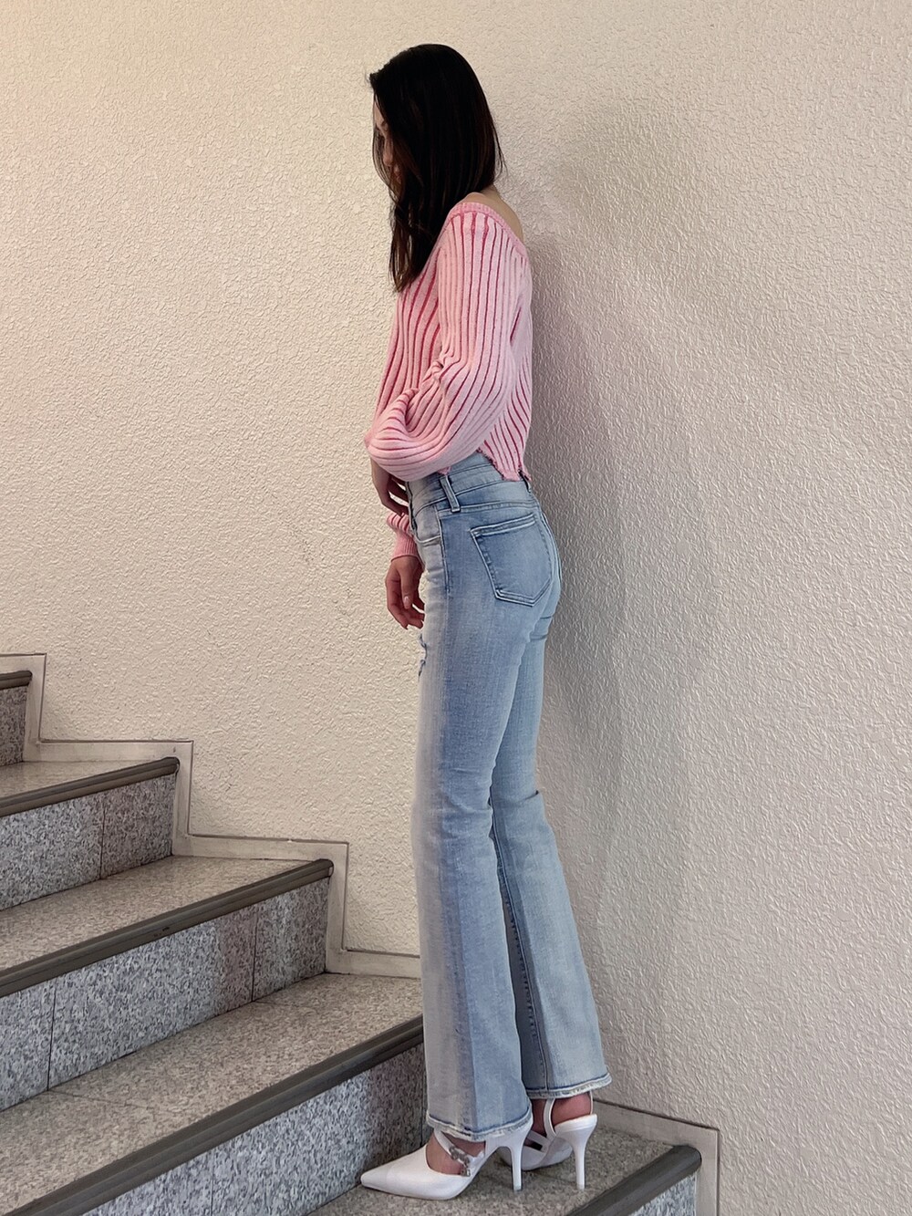 ブルー系のデニムパンツ、ピンク系のニット/セーター、ホワイト系のパンプスを着用したレディースの冬コーディネートの2枚目の写真