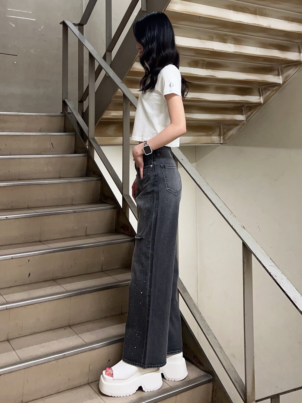 ホワイト系のTシャツ/カットソー、ブラック系のデニムパンツ、ホワイト系のサンダルを着用したレディースの春コーディネートの2枚目の写真