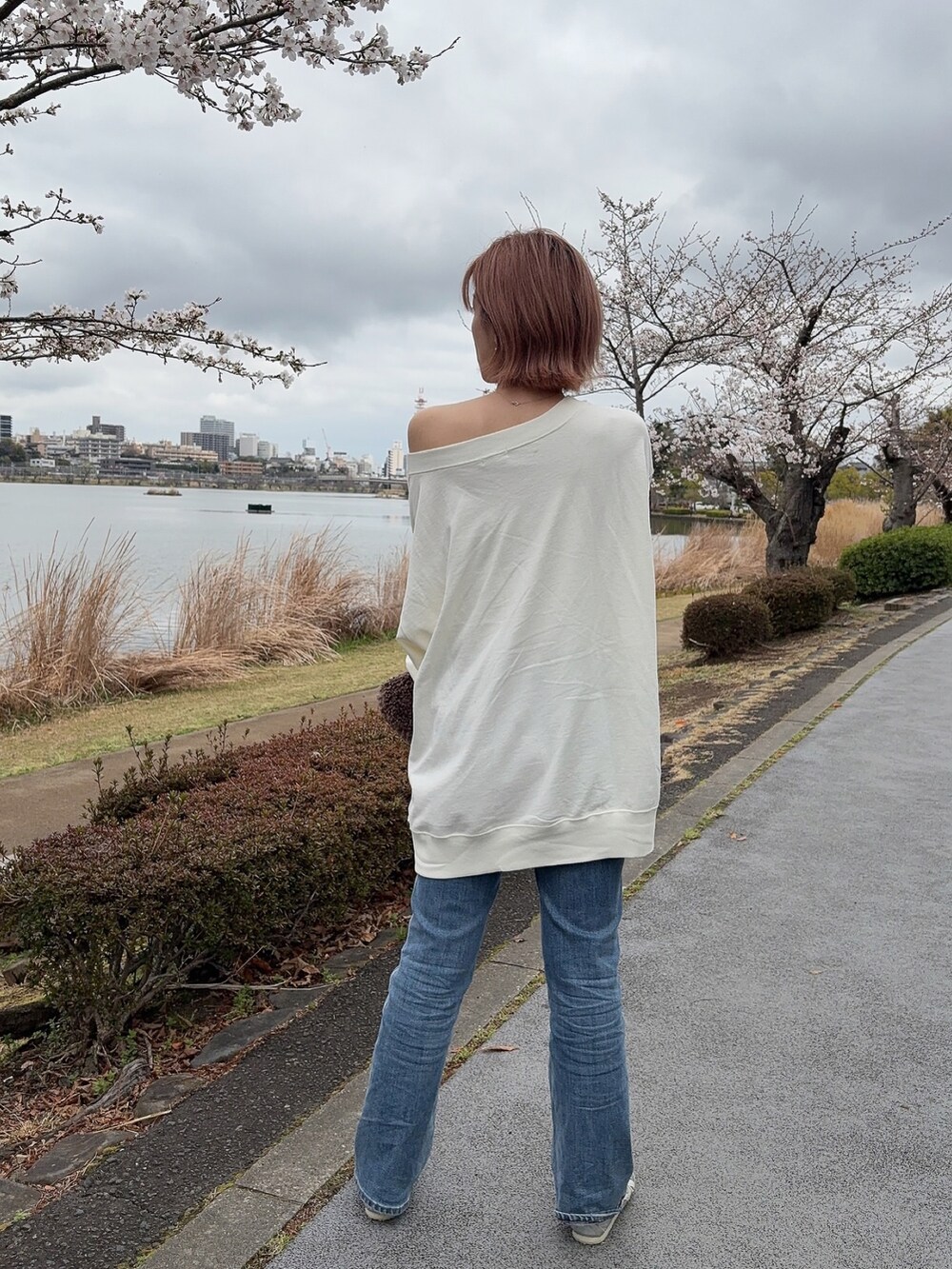 ブルー系のデニムパンツ、シルバー系のスニーカー、ホワイト系のTシャツ/カットソーを着用したレディースの春コーディネートの2枚目の写真