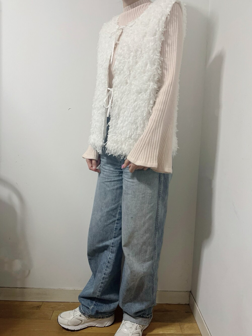ピンク系のニット/セーター、ホワイト系のベスト、ブルー系のデニムパンツを着用したレディースの春コーディネートの2枚目の写真
