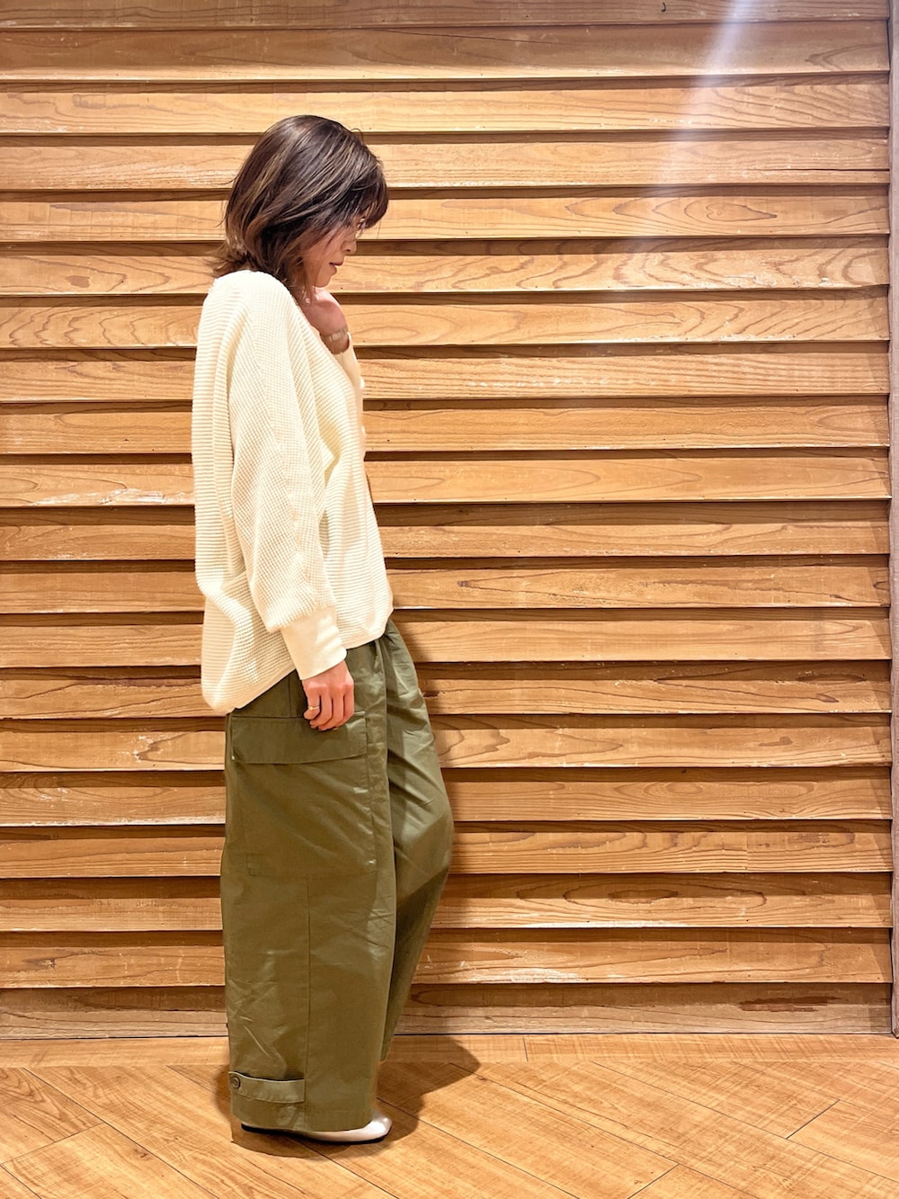 ホワイト系のニット/セーター、グリーン系のパンツ、シルバー系のシューズを着用したレディースの春コーディネートの2枚目の写真