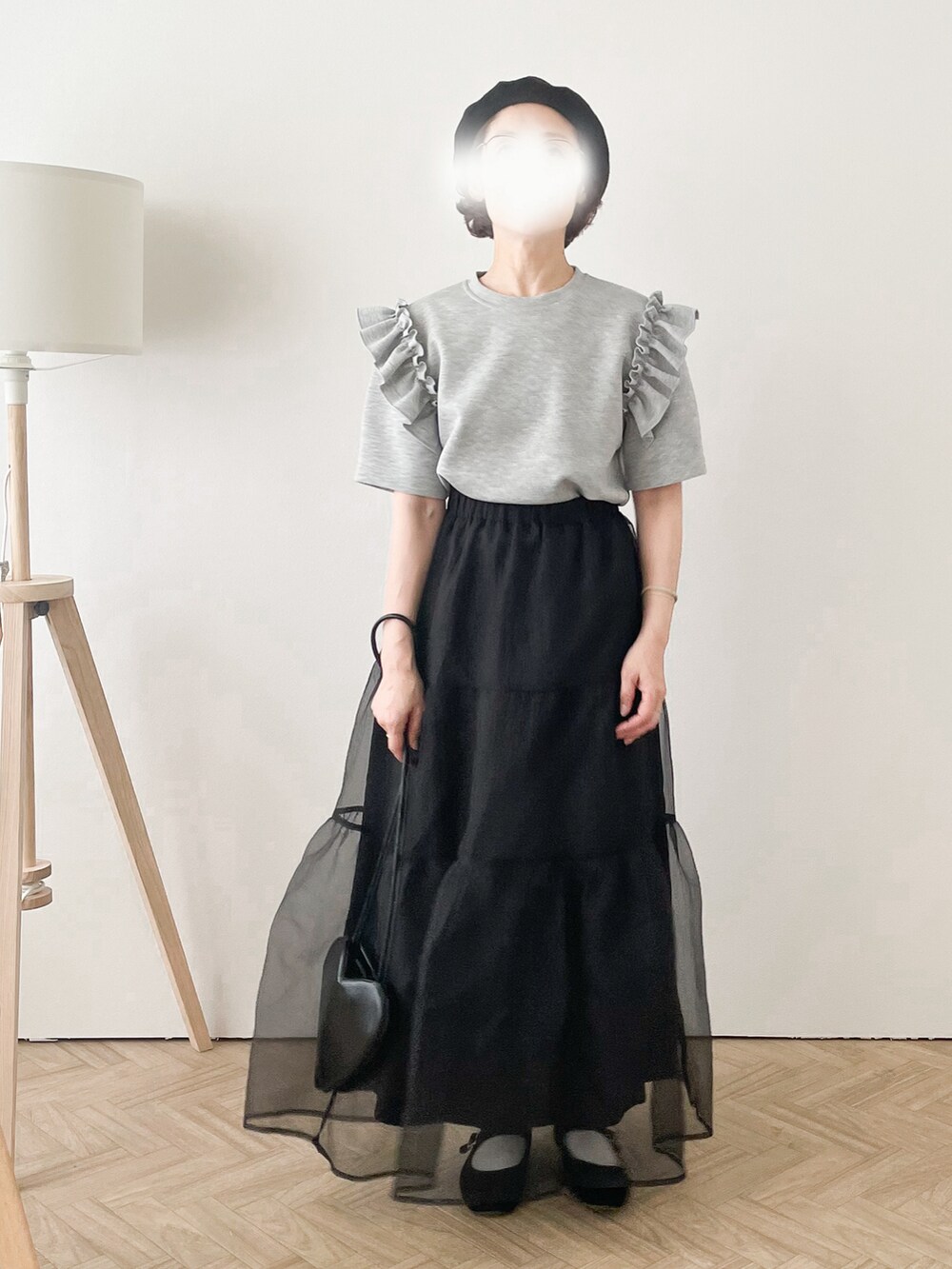 グレー系のTシャツ/カットソー、ブラック系のスカート、ブラック系のハンドバッグを着用したレディースの夏コーディネートの2枚目の写真