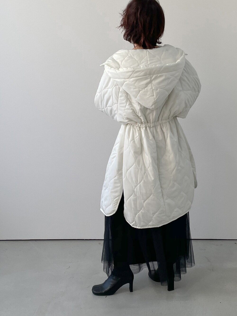 ホワイト系のダウンジャケット/コート、ブラック系のスカート、ブラック系のブーツを着用したレディースの冬コーディネートの3枚目の写真