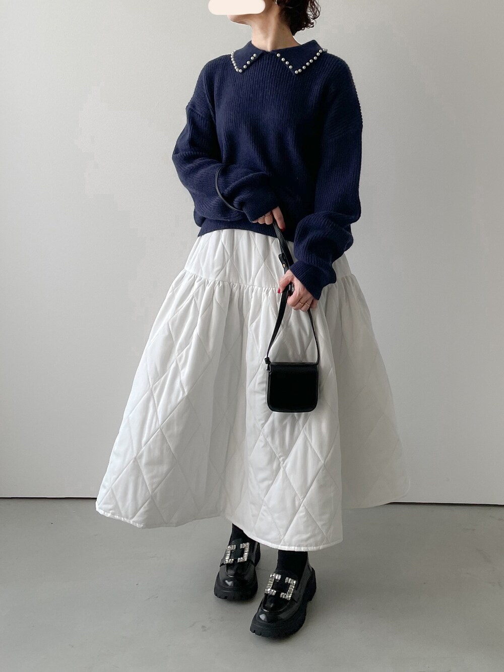 ブルー系のニット/セーター、ホワイト系のスカート、ブラック系のブーツを着用したレディースの冬コーディネートの2枚目の写真