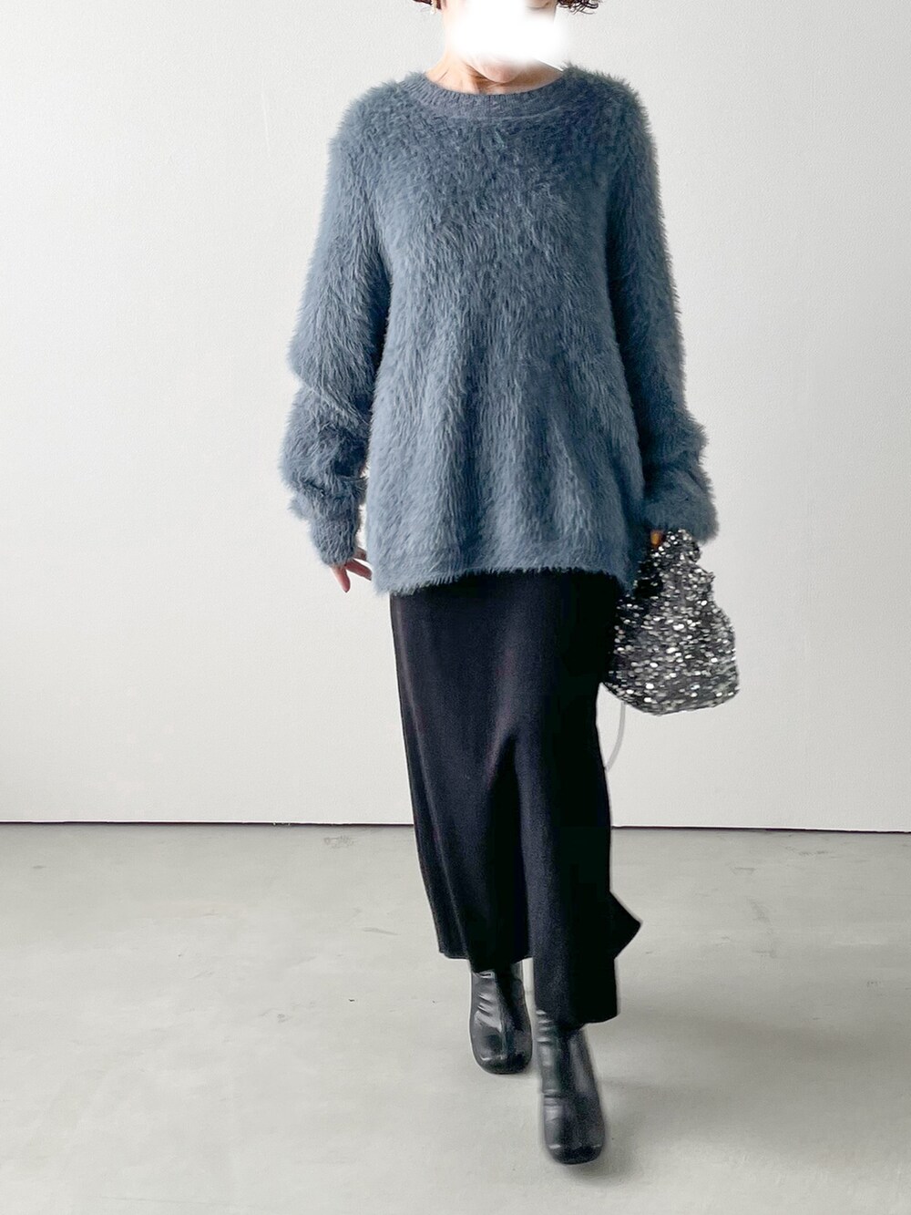 ブルー系のニット/セーター、ブラック系のスカート、ブラック系のブーツを着用したレディースの冬コーディネートの2枚目の写真