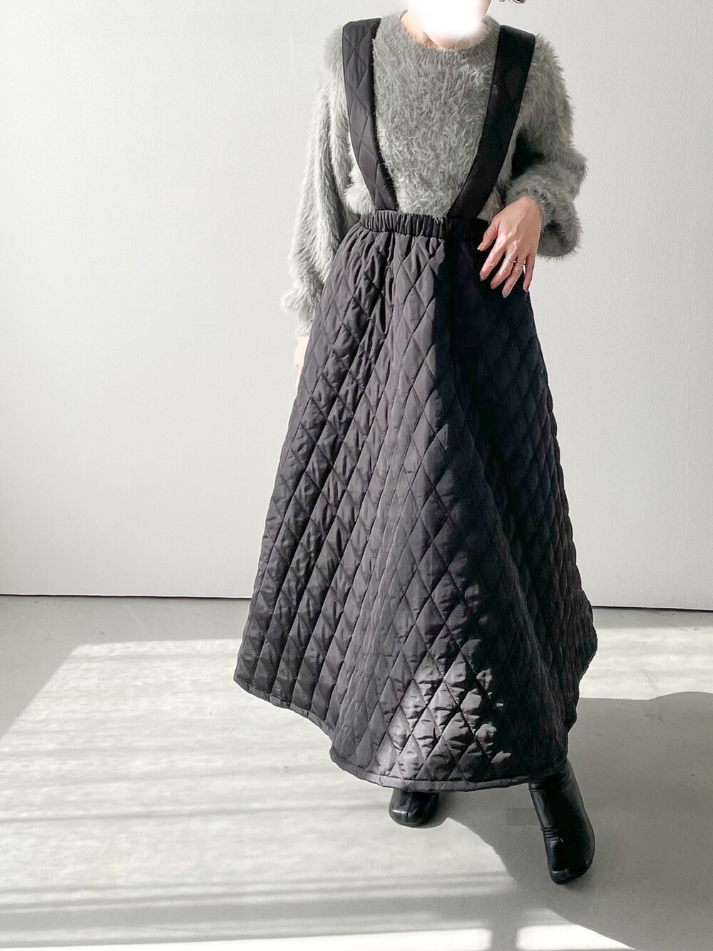 グレー系のニット/セーター、ブラック系のスカート、ブラック系のブーツを着用したレディースの冬コーディネートの2枚目の写真