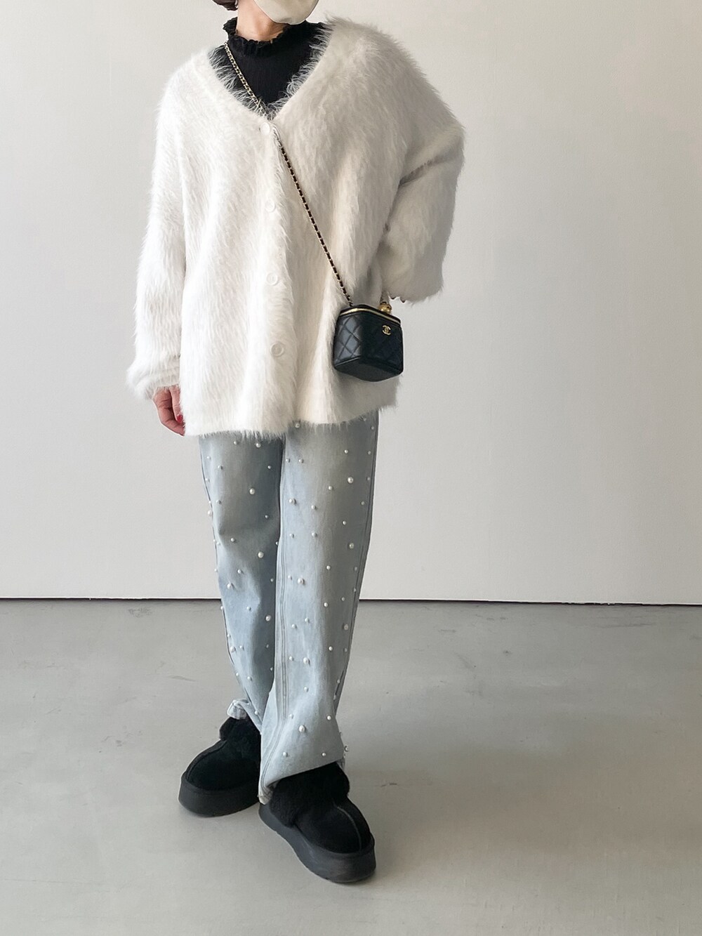 ホワイト系のニット/セーター、ブルー系のデニムパンツ、ブラック系のシャツ/ブラウスを着用したレディースの冬コーディネートの2枚目の写真