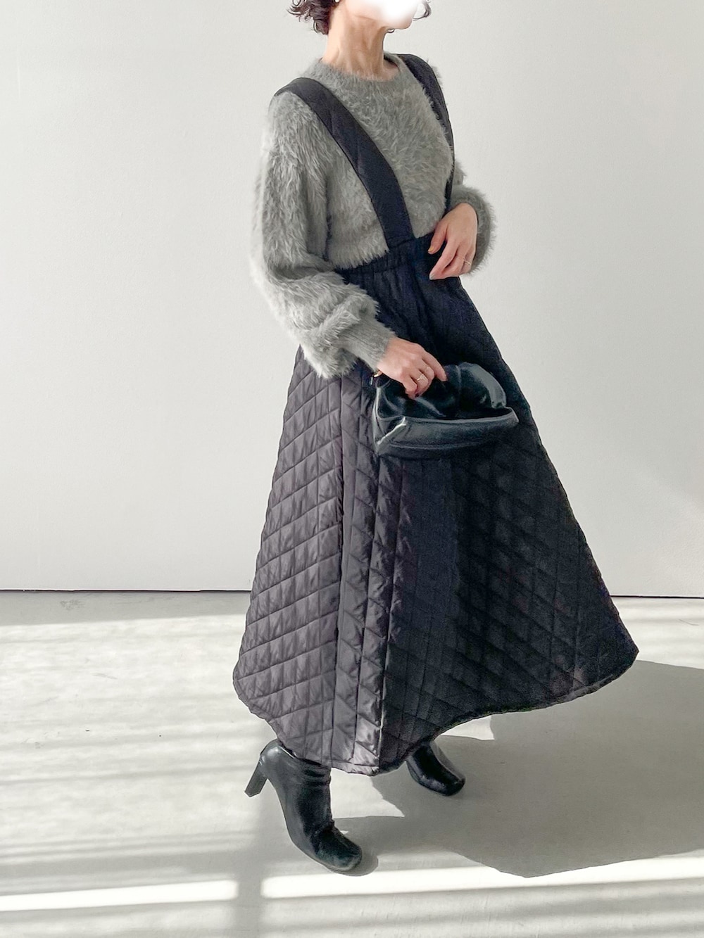 グレー系のニット/セーター、ブラック系のスカート、ブラック系のブーツを着用したレディースの冬コーディネートの3枚目の写真