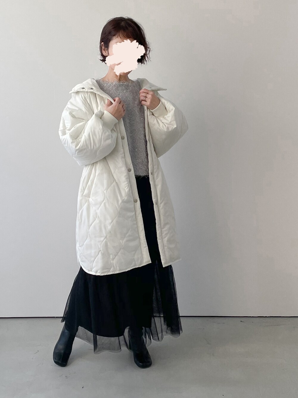 ホワイト系のダウンジャケット/コート、ブラック系のスカート、ブラック系のブーツを着用したレディースの冬コーディネートの2枚目の写真