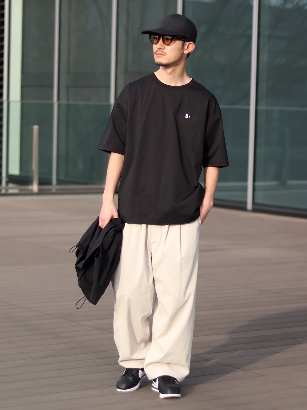 ブラック系のTシャツ/カットソー、ホワイト系のチノパンツ、ブラック系のスニーカーを着用したメンズの春コーディネートの4枚目の写真