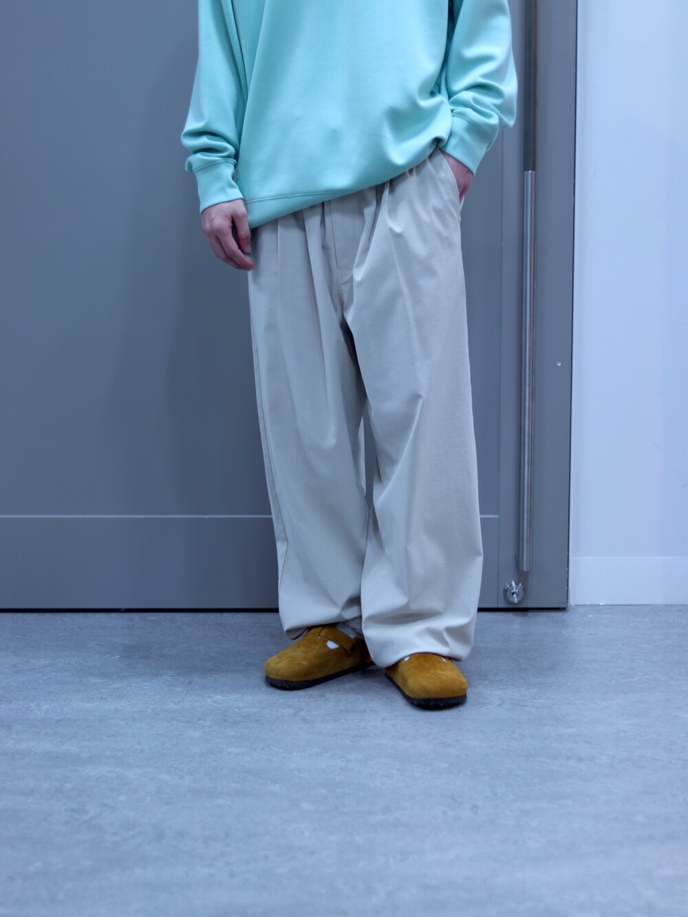 グリーン系のスウェット、ホワイト系のチノパンツ、ブラウン系のサングラスを着用したメンズの春コーディネートの4枚目の写真