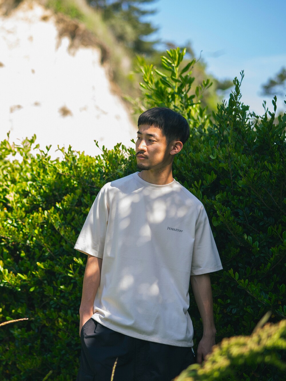 ベージュ系のTシャツ/カットソー、ブラック系のカーゴパンツを着用したメンズの夏コーディネートの3枚目の写真