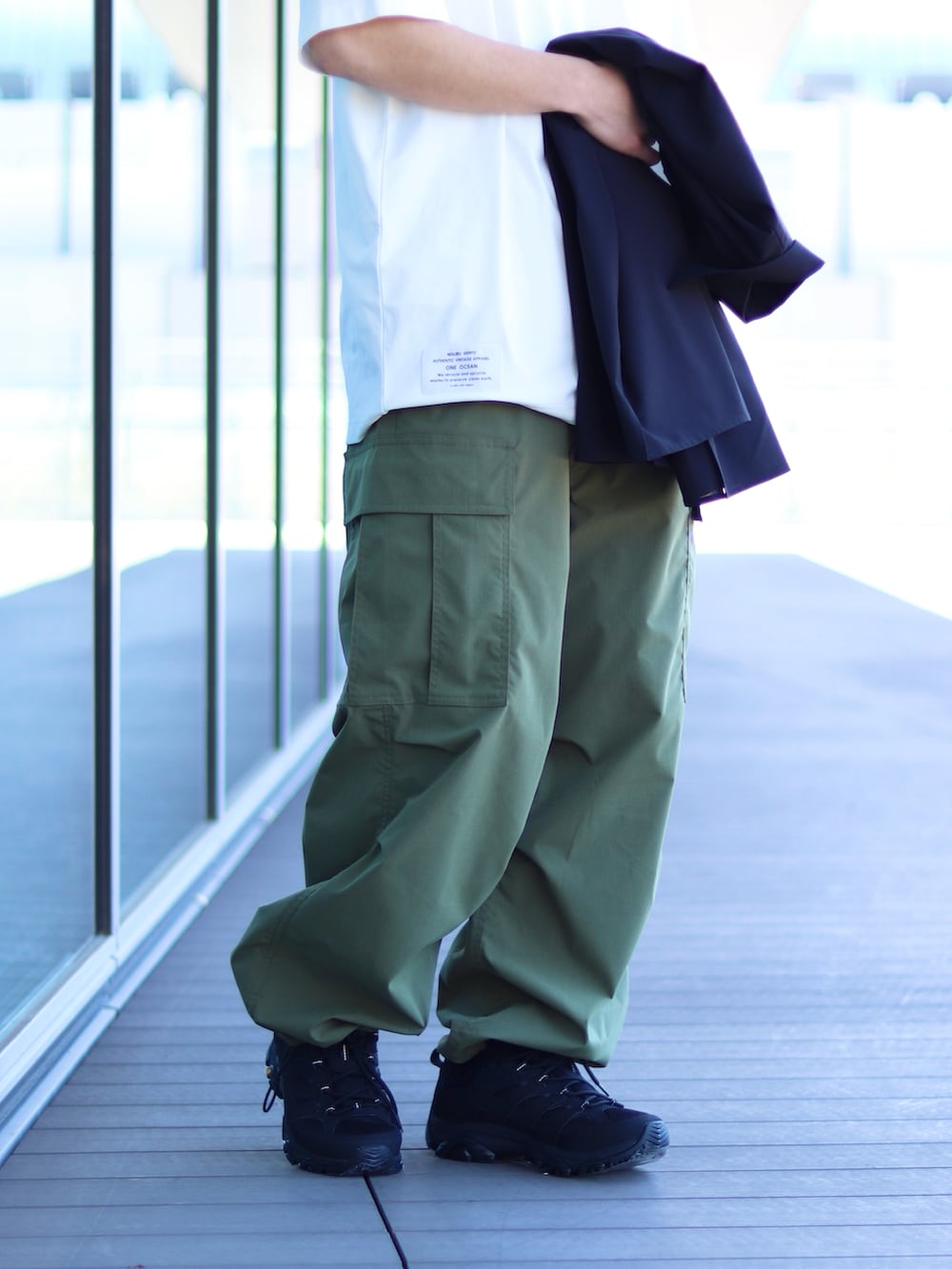 ホワイト系のTシャツ/カットソー、グリーン系のカーゴパンツ、ブラック系のスニーカーを着用したメンズの春コーディネートの3枚目の写真