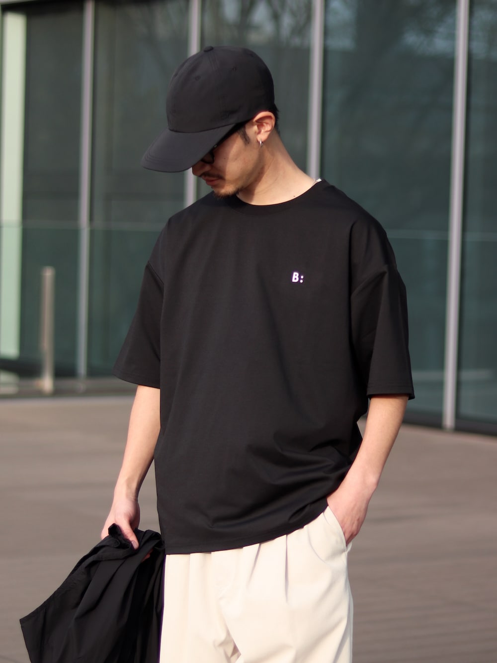 ブラック系のTシャツ/カットソー、ホワイト系のチノパンツ、ブラック系のスニーカーを着用したメンズの春コーディネートの3枚目の写真