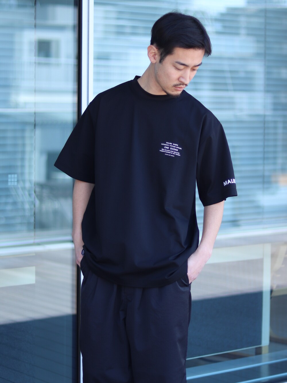 ブラック系のTシャツ/カットソー、ブラック系のチノパンツを着用したメンズの春コーディネートの2枚目の写真