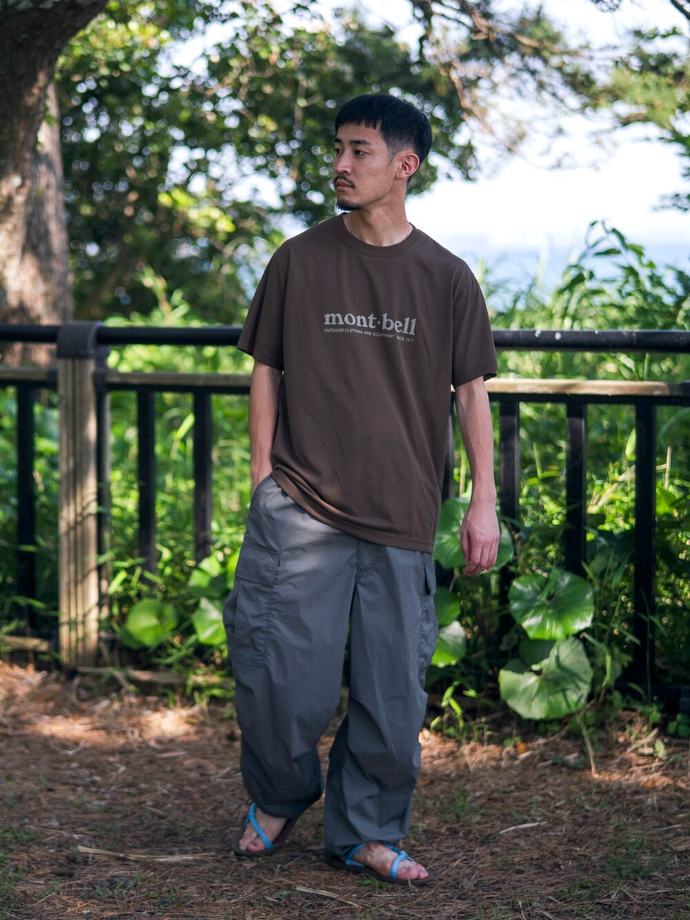 ブラウン系のTシャツ/カットソー、グリーン系のカーゴパンツ、ブラウン系のサンダルを着用したメンズの夏コーディネートの2枚目の写真