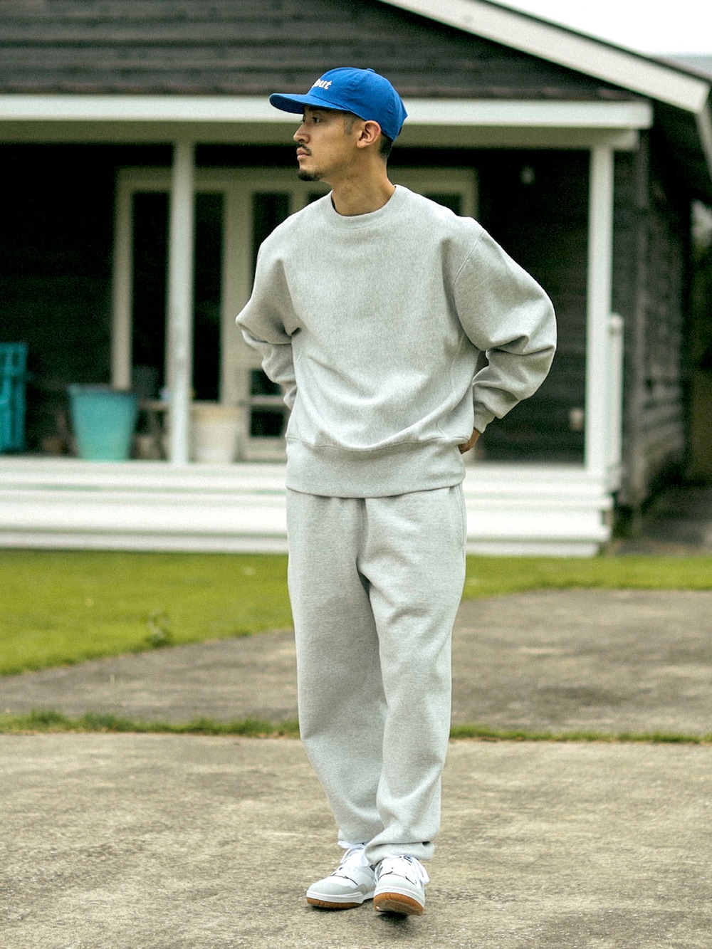 グレー系のスウェット、グレー系のスウェットパンツ、ブルー系のキャップを着用したメンズの秋コーディネートの2枚目の写真