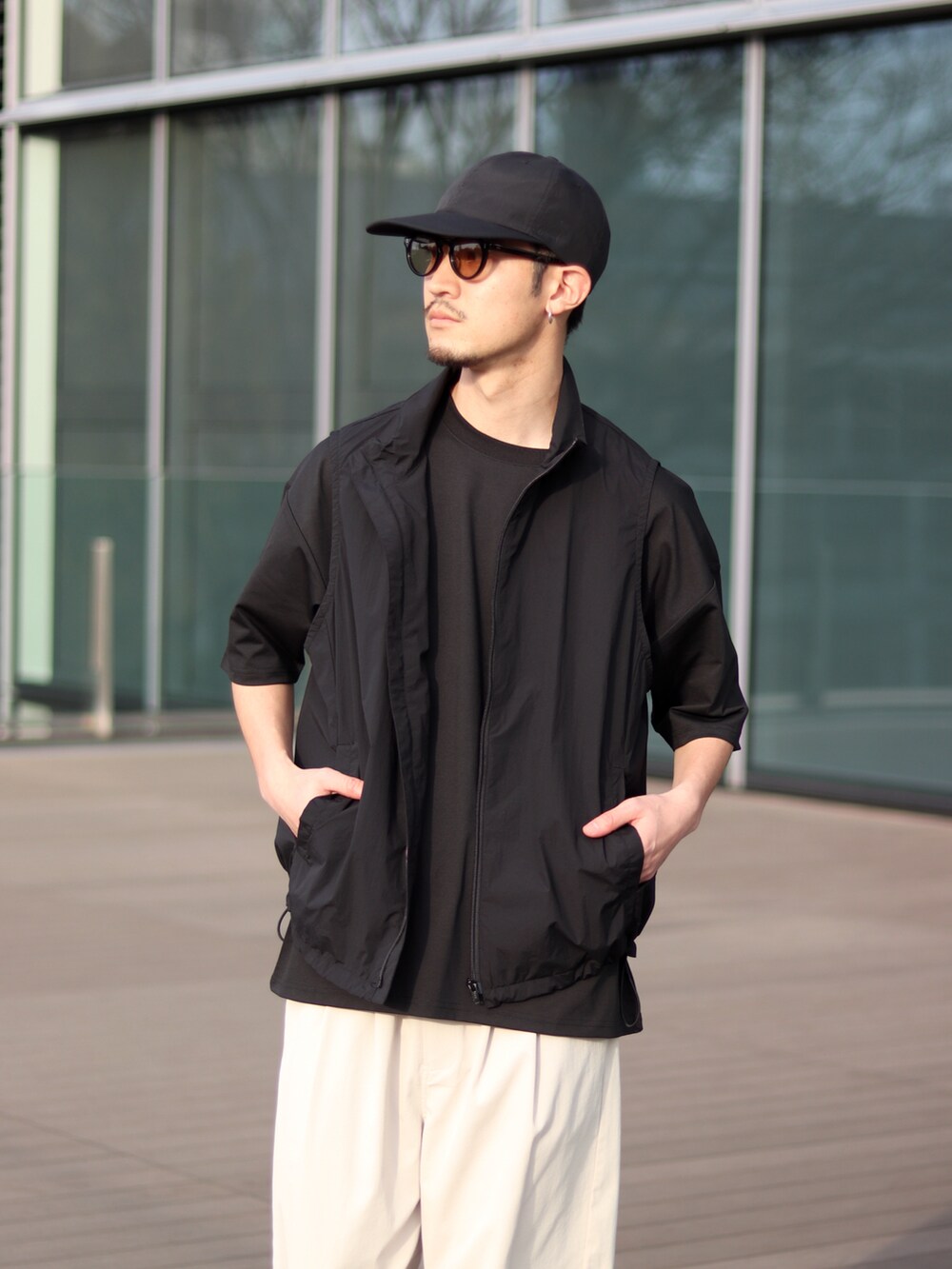 ブラック系のTシャツ/カットソー、ホワイト系のチノパンツ、ブラック系のスニーカーを着用したメンズの春コーディネートの2枚目の写真