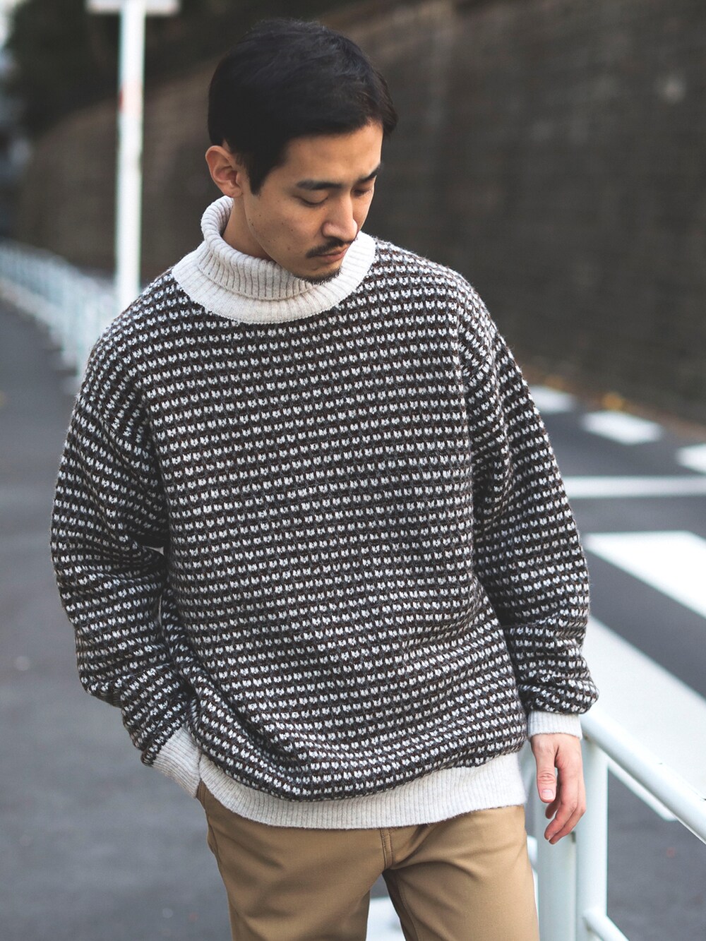 ホワイト系のニット/セーター、ベージュ系のチノパンツを着用したメンズの秋コーディネートの3枚目の写真